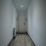 A simple and clean indoor hallway featuring a closed door and wooden flooring.