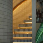 Elegant curved staircase with ambient lighting and tiled walls in a contemporary setting.
