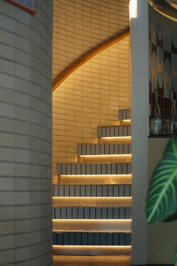 Elegant curved staircase with ambient lighting and tiled walls in a contemporary setting.